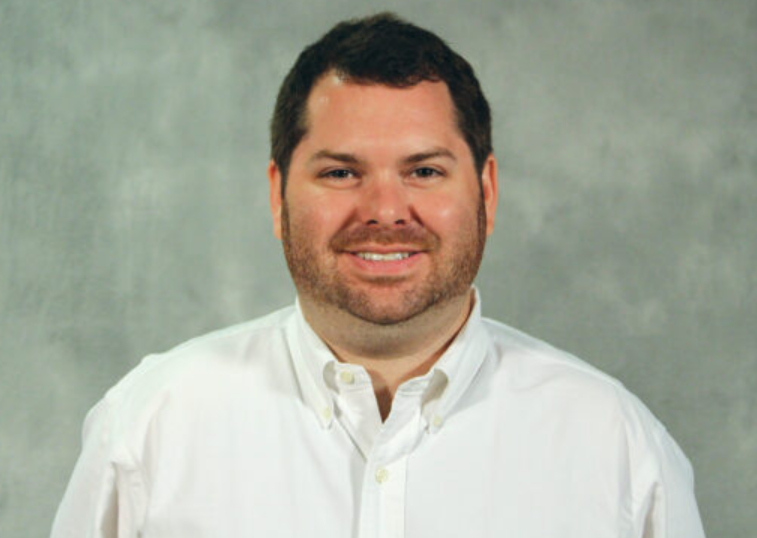 A man in a white shirt smiling at the camera