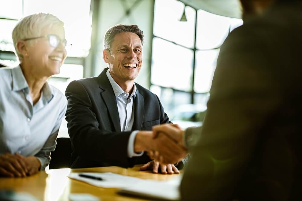 two people smiling shaking hands