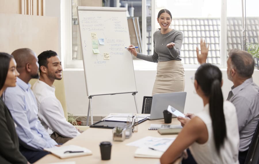 a women in front of a white board smiling